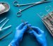 Preparing for plastic surgery. Doctor's hands takes scalpel on blue background with surgical tools top view.